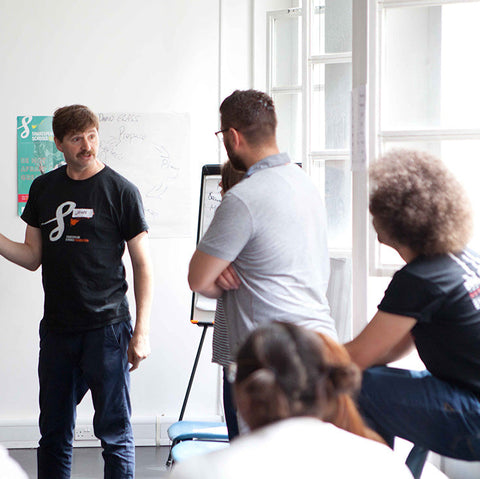 Person giving a presentation to an audience in a classroom setting.